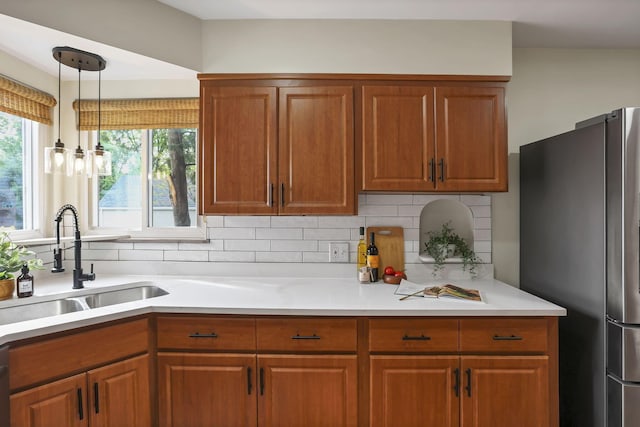 kitchen featuring a sink, freestanding refrigerator, brown cabinets, and a wealth of natural light