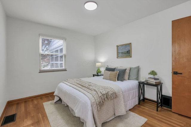 bedroom with baseboards, wood finished floors, and visible vents