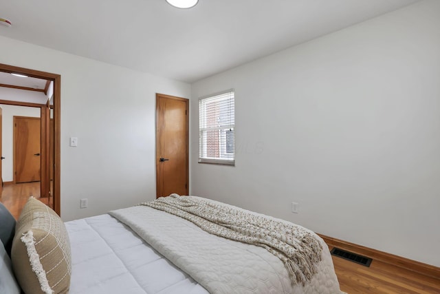 bedroom featuring baseboards, visible vents, and wood finished floors