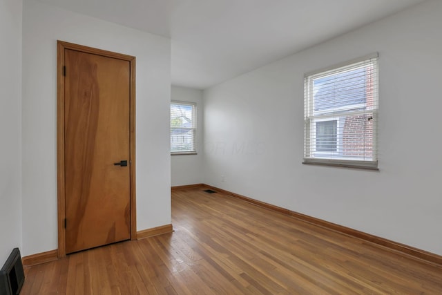 spare room with baseboards and wood finished floors
