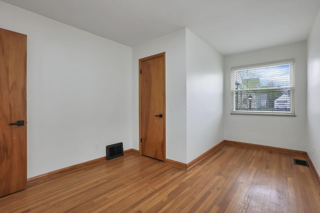 spare room with baseboards, visible vents, and hardwood / wood-style flooring
