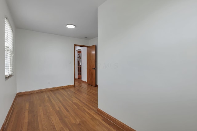spare room with baseboards and wood finished floors