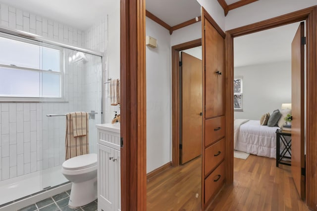 ensuite bathroom with crown molding, toilet, a shower stall, wood finished floors, and ensuite bathroom