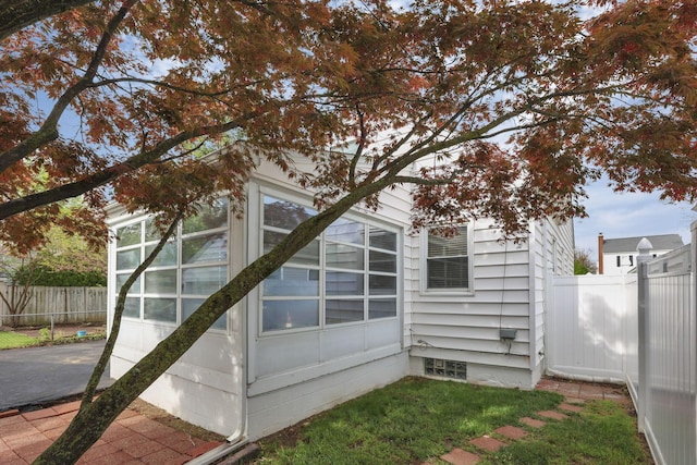 view of home's exterior with a sunroom, fence, and driveway