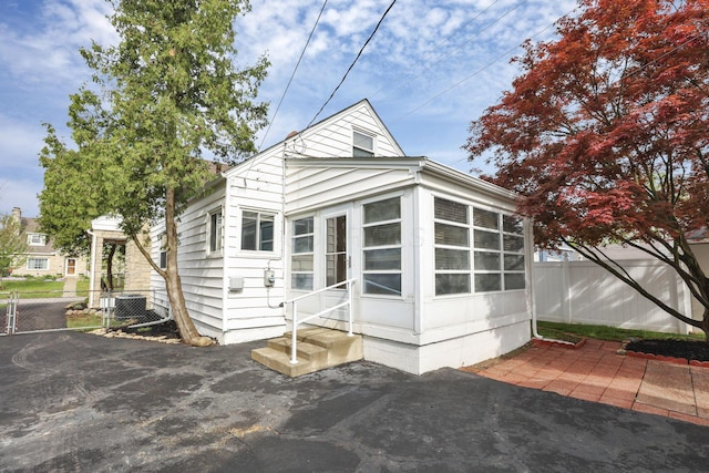 rear view of property with central AC, fence, a patio, a sunroom, and entry steps