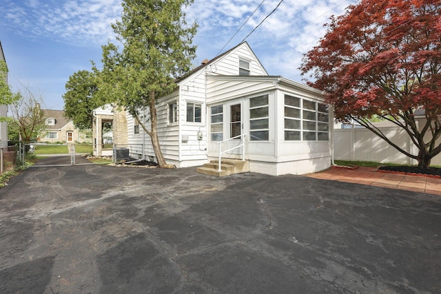 view of front of property featuring entry steps, fence, central AC unit, and a sunroom