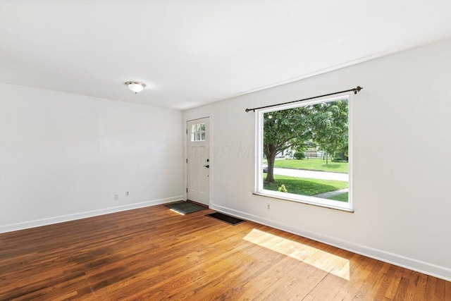 empty room with visible vents, baseboards, and wood-type flooring