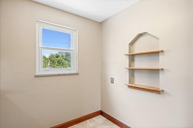 empty room featuring baseboards and tile patterned flooring