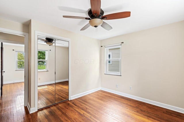 unfurnished bedroom with a closet, baseboards, a ceiling fan, and hardwood / wood-style floors