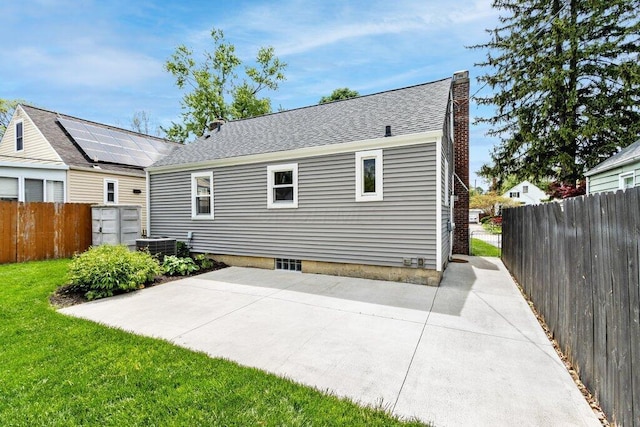 back of house with a chimney, a patio, fence, and a lawn