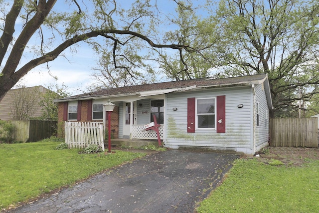 5143 Rutledge Dr N, Columbus, OH 43232 - view of front facade with covered porch, aphalt driveway, fence, and a front lawn