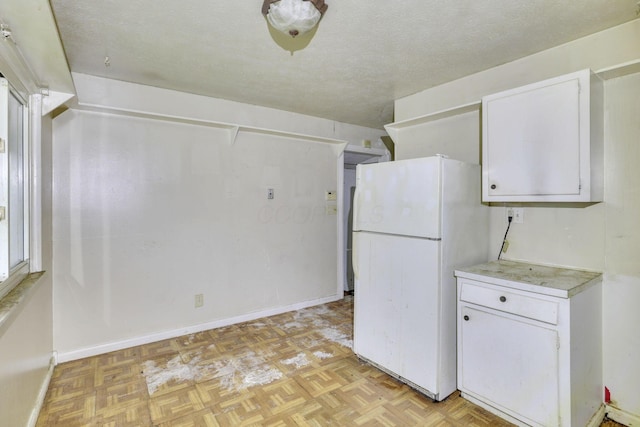 5143 Rutledge Dr N, Columbus, OH 43232 - kitchen with freestanding refrigerator, white cabinetry, a textured ceiling, and light countertops