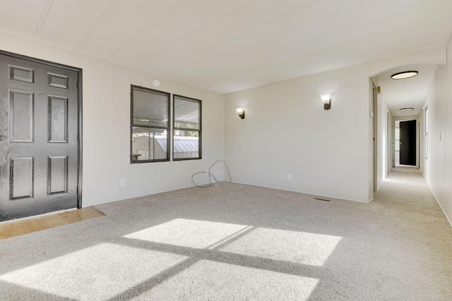 empty room featuring carpet floors and arched walkways