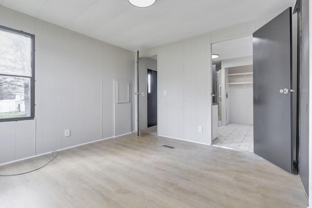 unfurnished bedroom with a walk in closet, visible vents, and wood finished floors