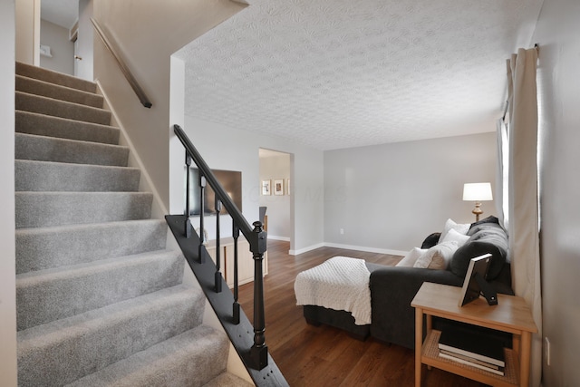 stairs with wood finished floors, a textured ceiling, and baseboards