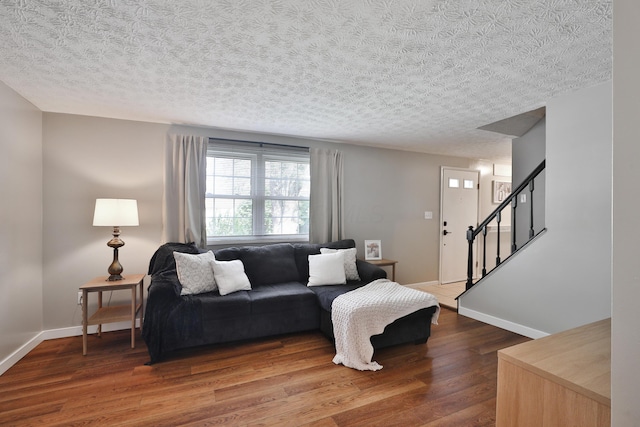 living area featuring wood finished floors, a textured ceiling, stairway, and baseboards