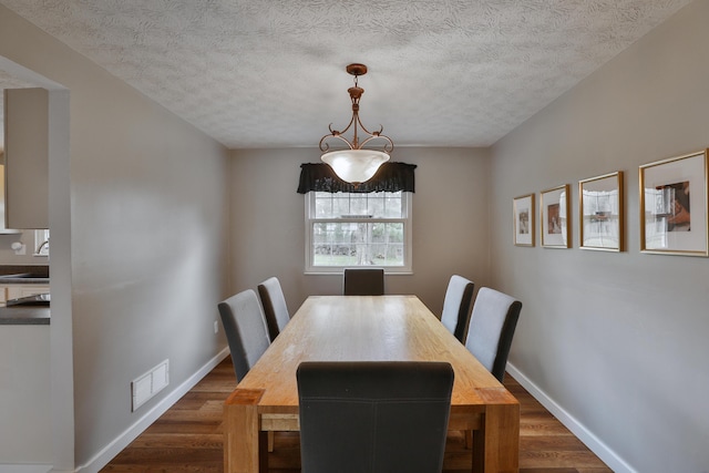 dining space featuring dark wood-style floors, baseboards, and a textured ceiling