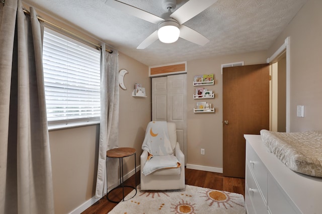 sitting room featuring dark wood-style floors, a ceiling fan, a textured ceiling, and baseboards