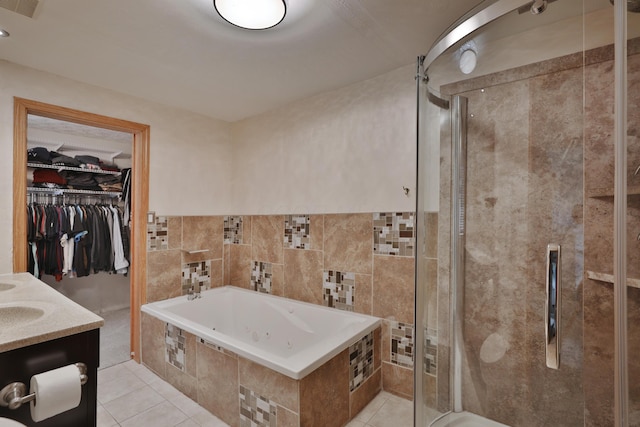 full bathroom with tile patterned flooring, a shower stall, a jetted tub, a spacious closet, and tile walls