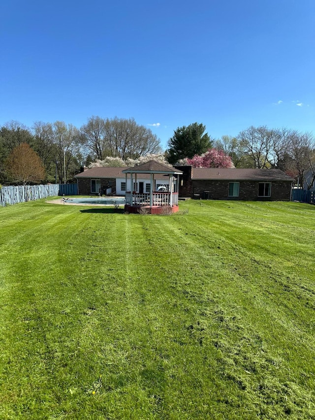 rear view of house featuring fence, a lawn, and a deck
