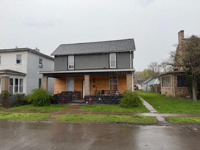 rear view of property with a porch and a lawn