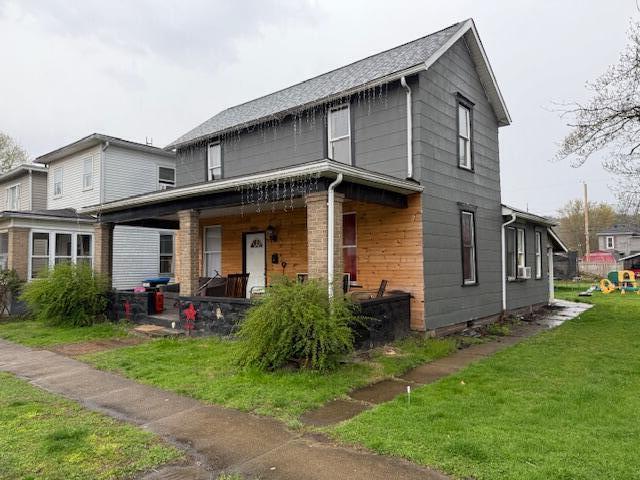 rear view of house featuring covered porch and a yard