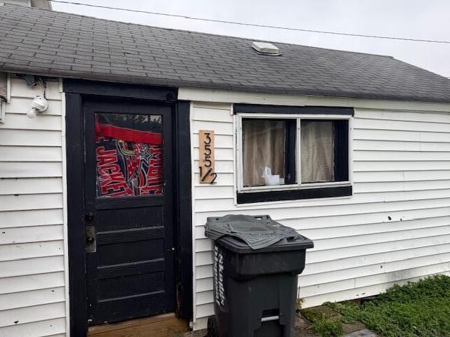 doorway to property featuring a shingled roof
