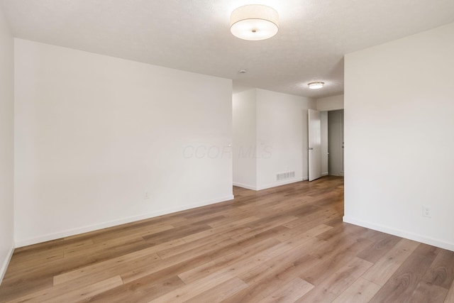 unfurnished room featuring baseboards, visible vents, and light wood-style floors