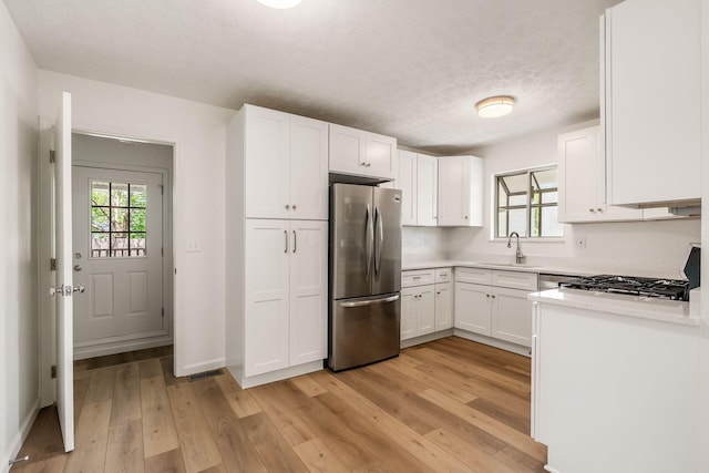 kitchen featuring plenty of natural light, freestanding refrigerator, light wood-style flooring, and light countertops