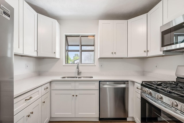 kitchen featuring light countertops, stainless steel appliances, white cabinets, and a sink