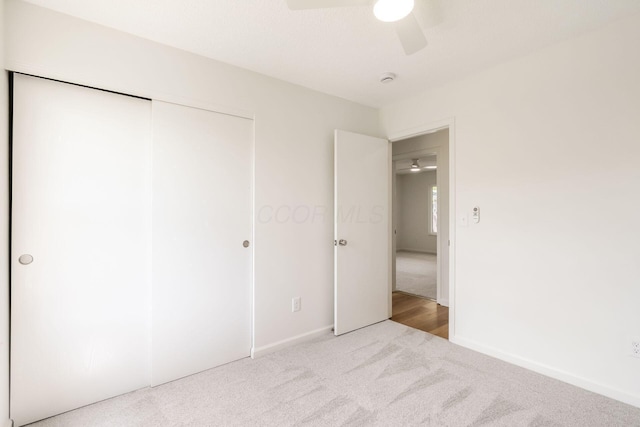 unfurnished bedroom featuring baseboards, ceiling fan, carpet, and a closet
