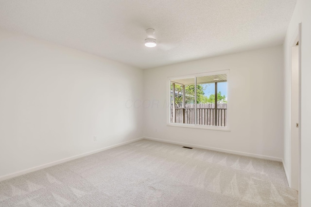 spare room with a textured ceiling, baseboards, and light carpet