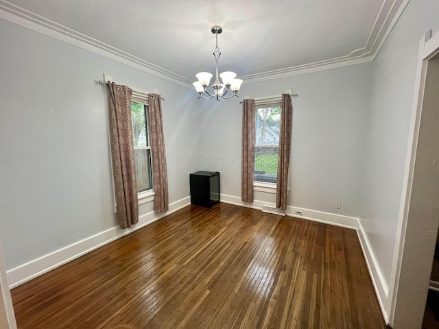 spare room with baseboards, ornamental molding, a notable chandelier, and hardwood / wood-style floors