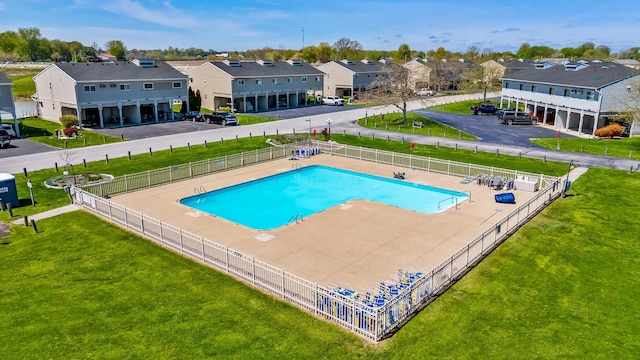 pool with a residential view, fence, and a yard