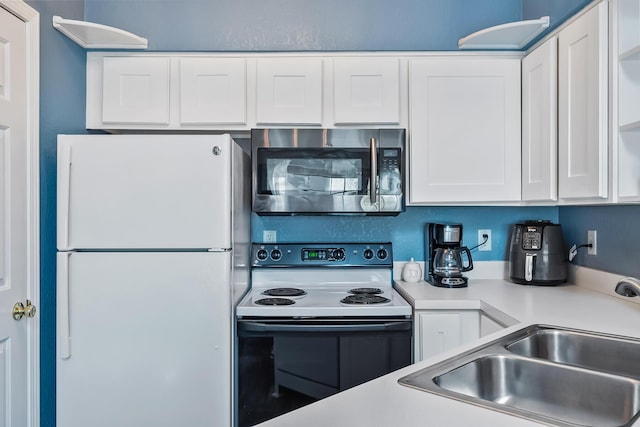 kitchen featuring electric range, light countertops, white cabinets, stainless steel microwave, and freestanding refrigerator