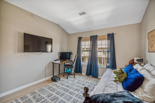 bedroom with baseboards, vaulted ceiling, wood finished floors, and visible vents