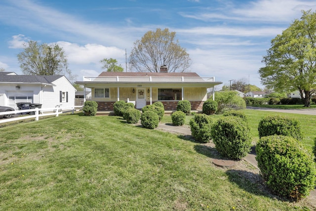 view of front of home with a porch, brick siding, a chimney, and a front lawn