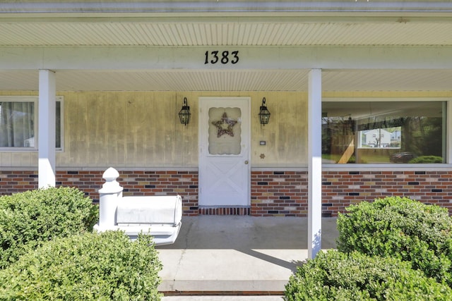 entrance to property with brick siding and covered porch