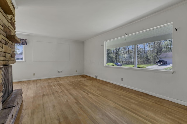 unfurnished living room featuring visible vents, light wood-style flooring, and a wealth of natural light