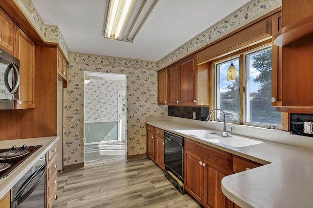 kitchen featuring a sink, wallpapered walls, light wood-style flooring, and dishwasher
