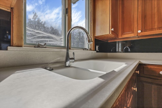 interior details with brown cabinetry, a sink, and light countertops