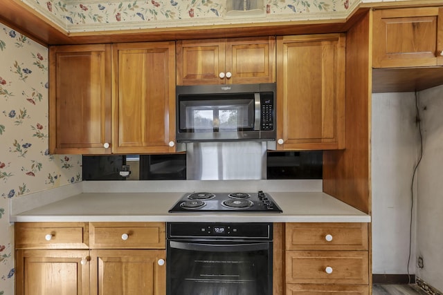 kitchen with light countertops, brown cabinets, wallpapered walls, and black appliances