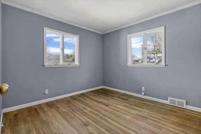 unfurnished room with crown molding, baseboards, visible vents, and wood finished floors