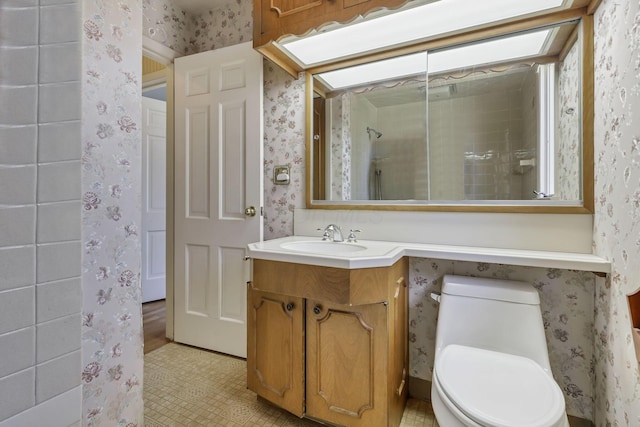 bathroom with toilet, wallpapered walls, and vanity