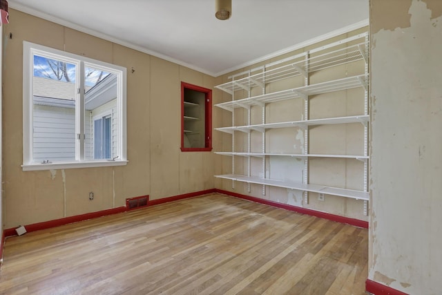 unfurnished room with crown molding, baseboards, wood finished floors, and visible vents
