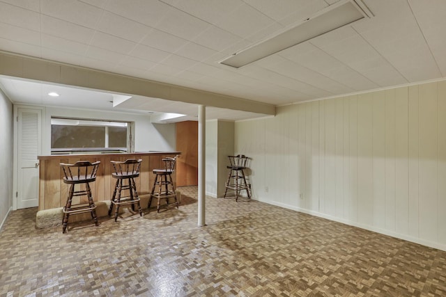 bar featuring baseboards, wood walls, and bar