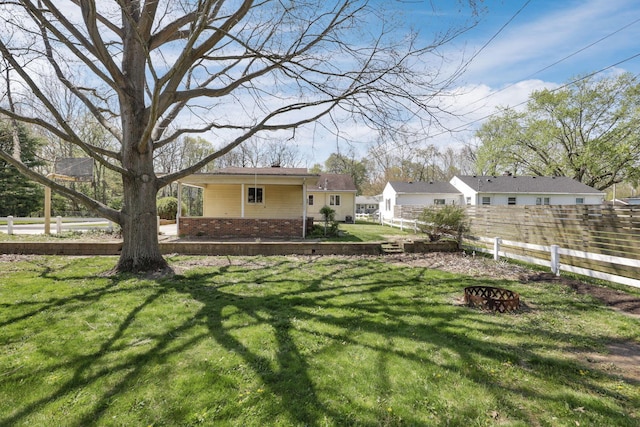 view of yard with fence and a fire pit
