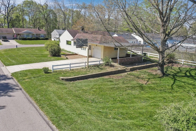 view of yard featuring fence, an attached garage, concrete driveway, and a residential view