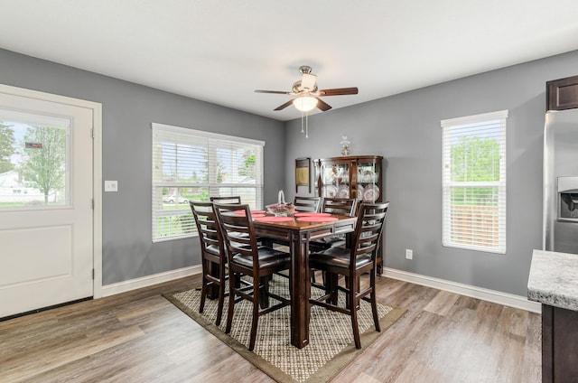 dining room featuring baseboards, ceiling fan, light wood-style flooring, and a wealth of natural light