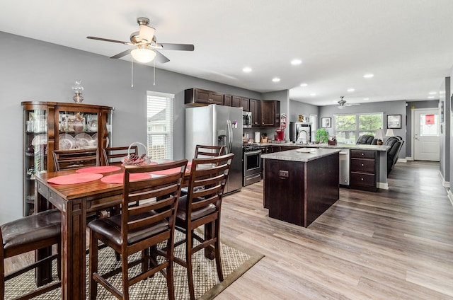 kitchen featuring ceiling fan, a kitchen island, dark brown cabinets, stainless steel appliances, and recessed lighting